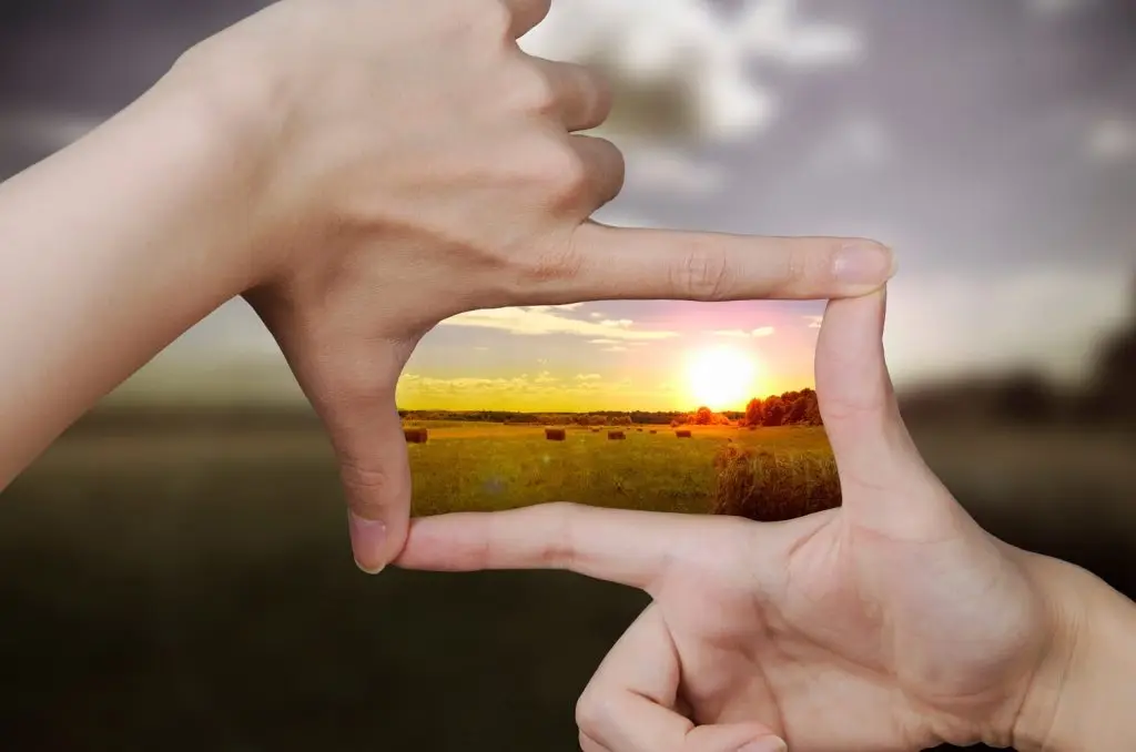 Image of someone framing a sunset with their fingers.