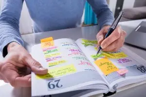 Photo of person writing in a calendar or daily to-do list.