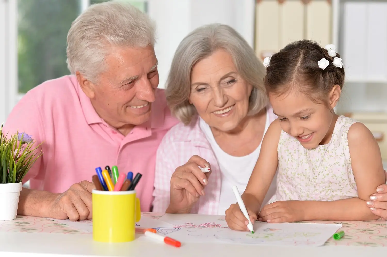 Photo of grandparents drawing with a young girl.