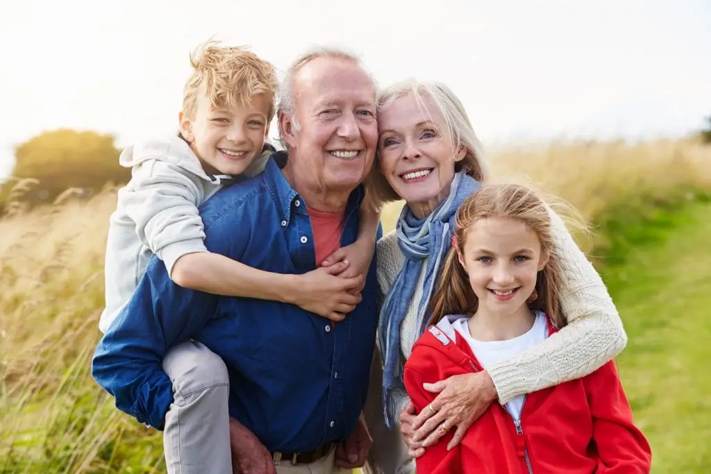 Photo of grandparents with their grandchildren outdoors.