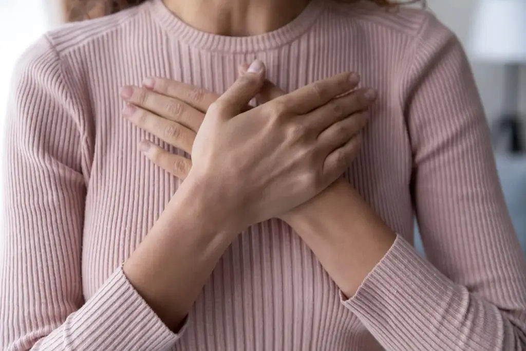 Photo of grateful woman holding hands over her heart.