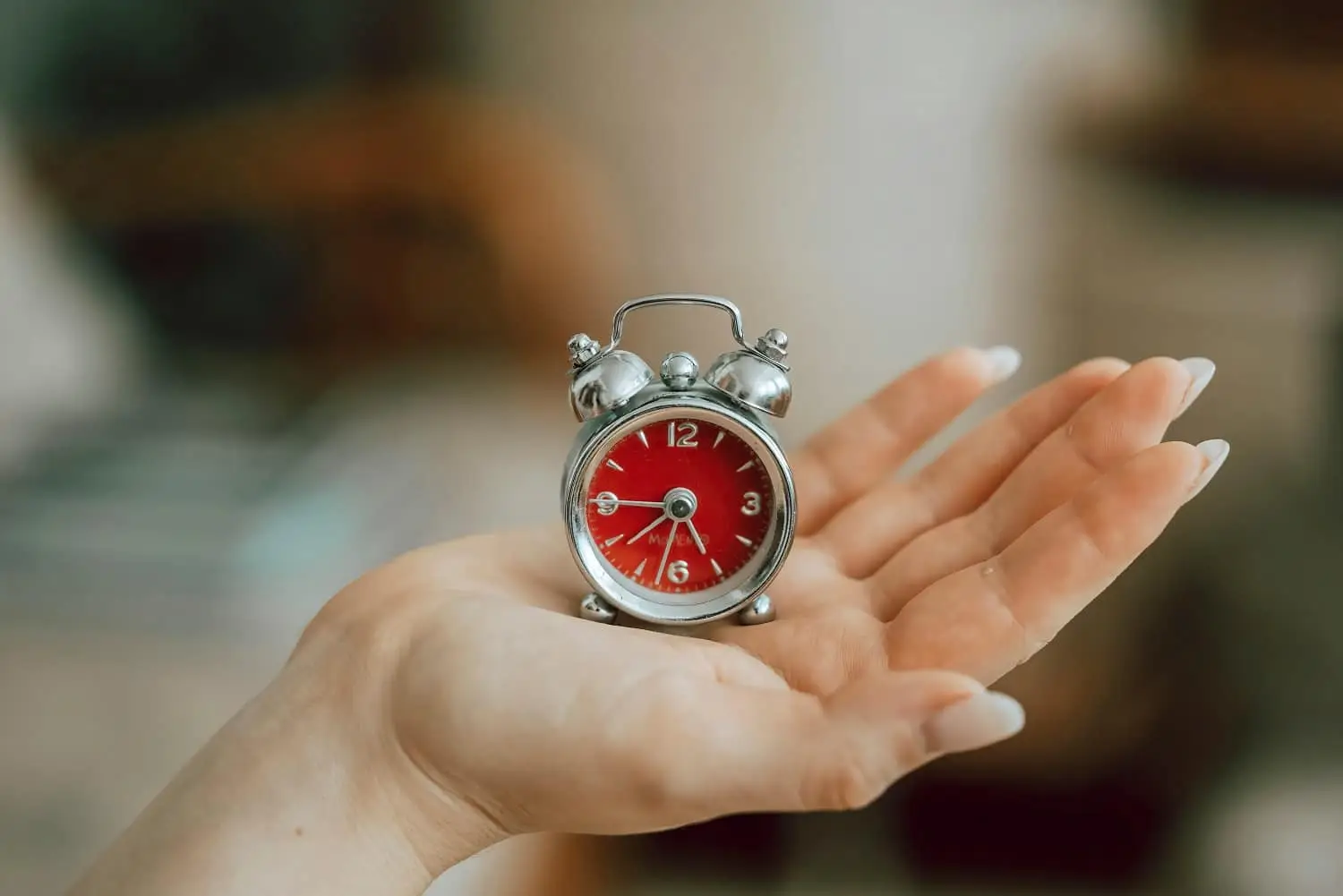 Photo of person holding tiny clock in their palm.