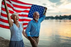 Older Americans carrying a flag at sunset.
