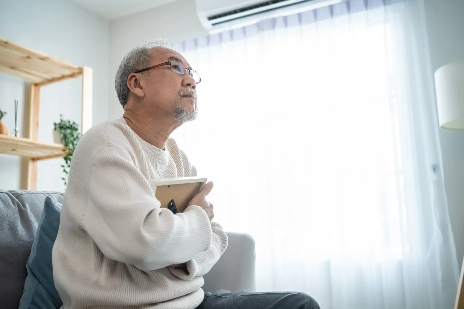 Photo of an older man clutching a picture frame to his chest.
