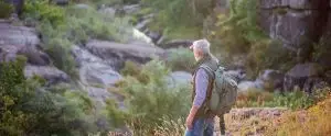 Photo of an older man walking outdoors among nature.