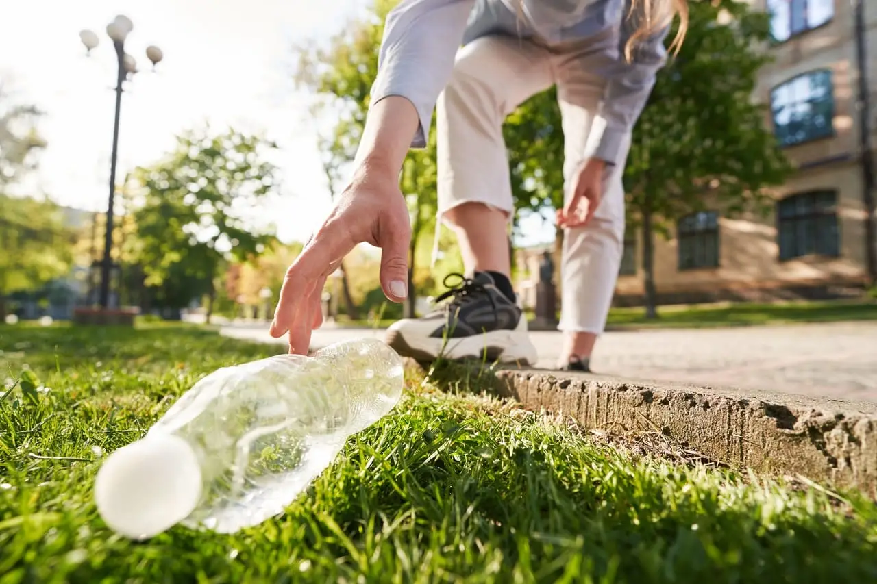 Photo of someone picking up a piece of litter.
