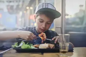 Photo of a young teen eating a meal.