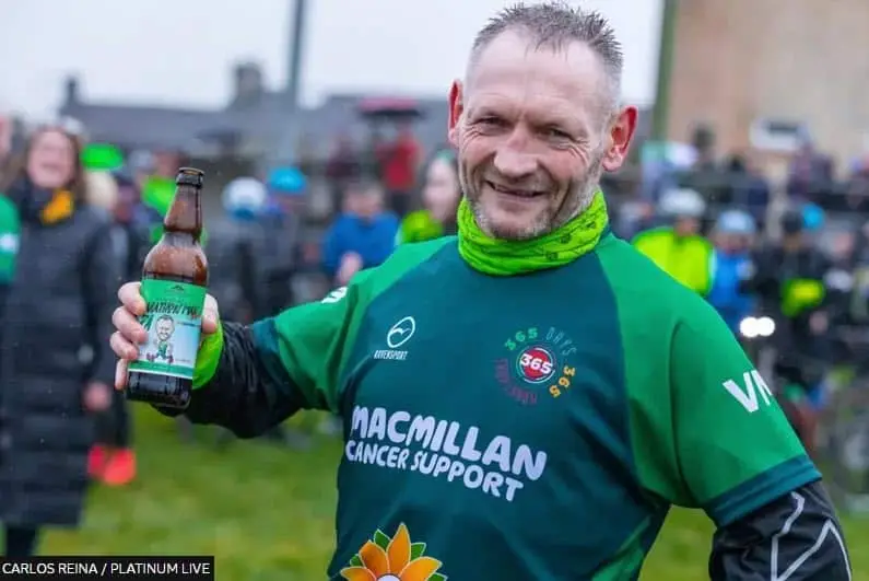 Gary McKee celebrates after completing 365 marathons in 2022. Photo by Carlos Reina at Platinum Live and published by the BBC.