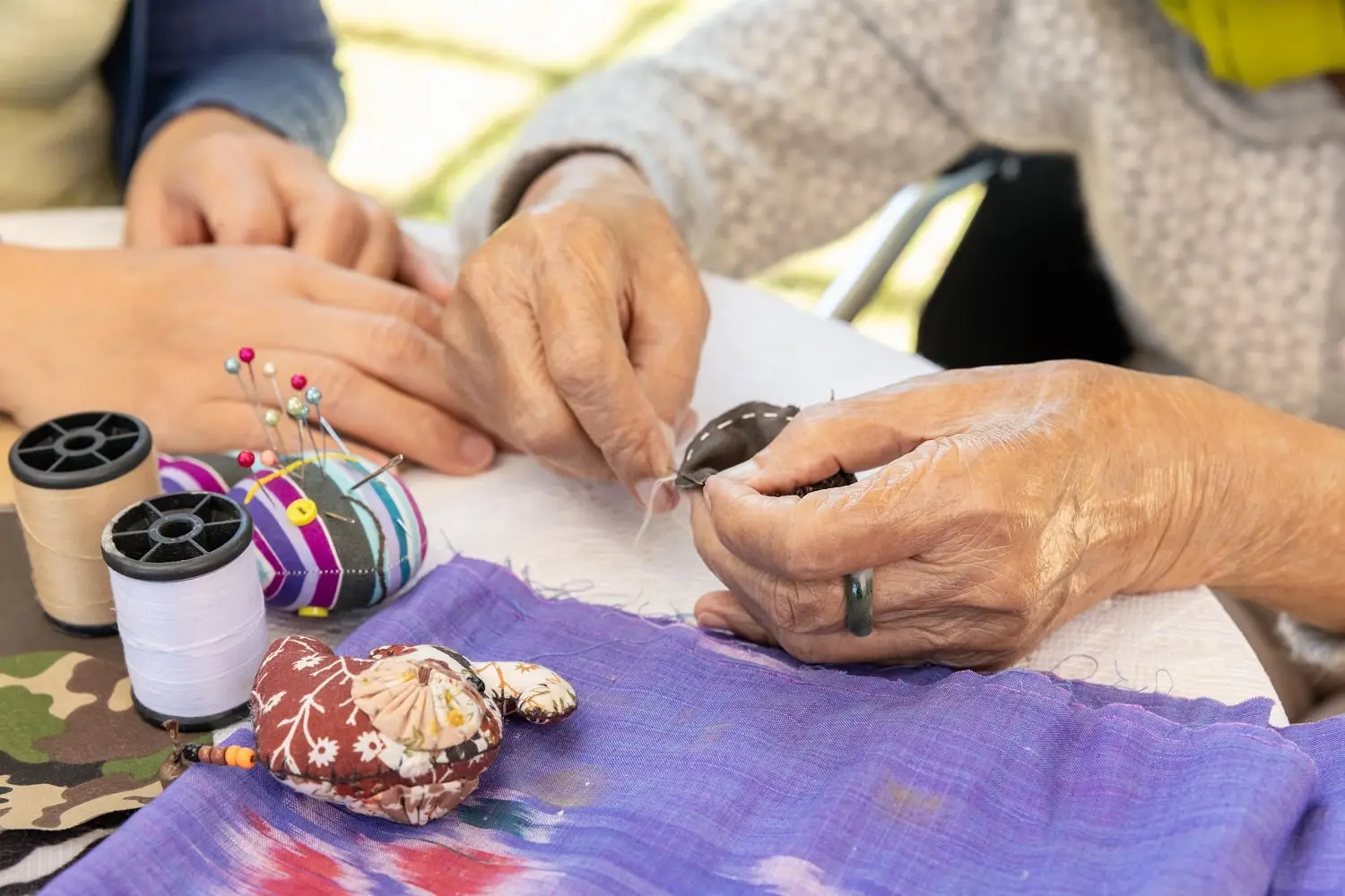Photo of daughter helping elderly mother with crafts.