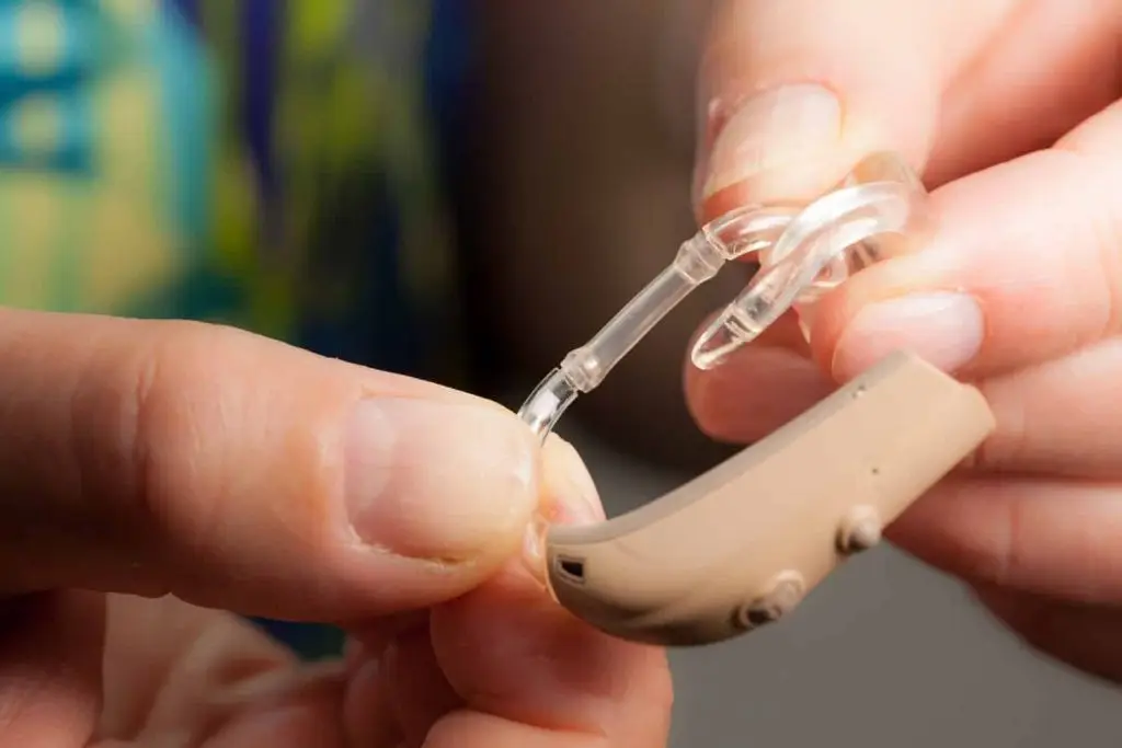 Photo of a seasoned citizen holding a hearing aid.