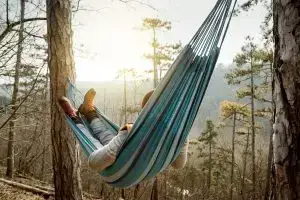 Photo of a man relaxing on a hammock in the wilderness.