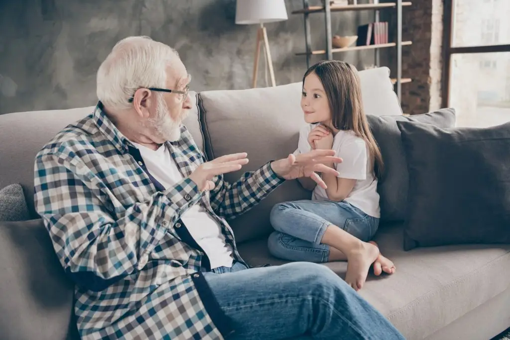 Photo of a grandfather sharing a story with his excited granddaughter.