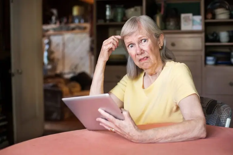 Photo of a confused woman staring at a computer tablet.